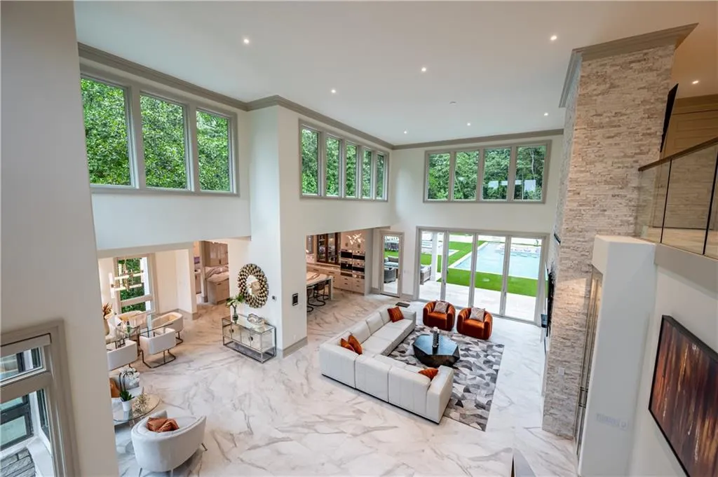 Soaring two-story great room with floor-to-ceiling windows framing natural light and verdant landscape views