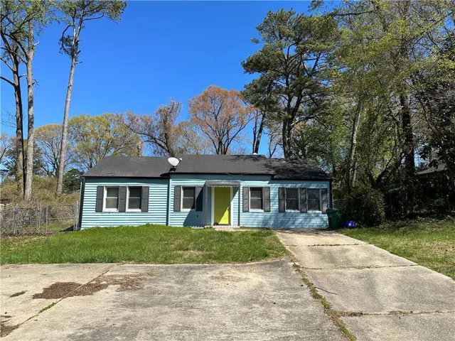 Light blue siding with dark shutters, bright yellow front door, and a black shingle roof