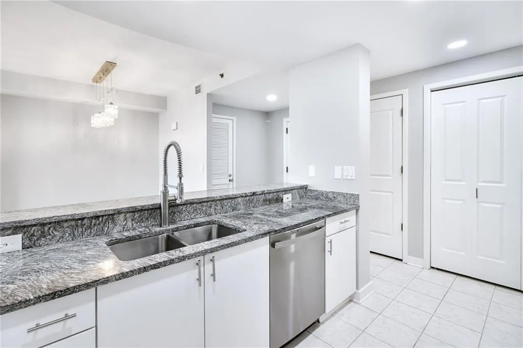 Kitchen featuring dishwasher, white cabinets, dark stone countertops, light tile patterned floors, and recessed lighting