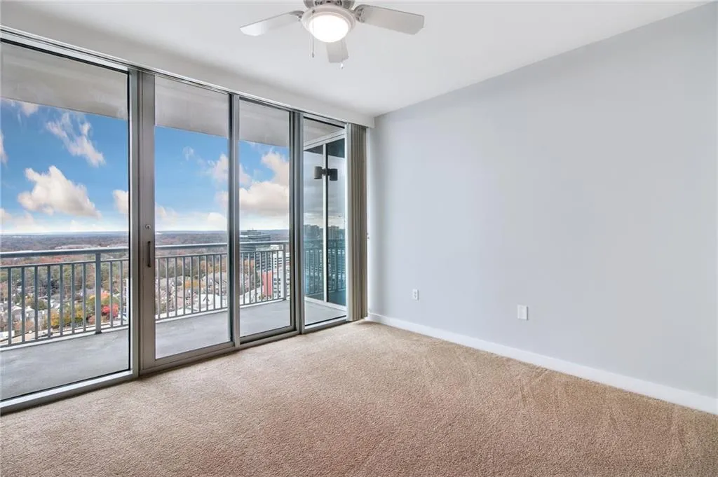 Empty room with carpet floors, ceiling fan, and floor to ceiling windows
