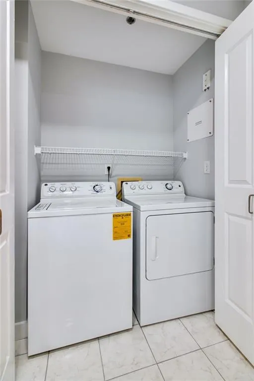 Washroom featuring washer and clothes dryer and light marble finish floors