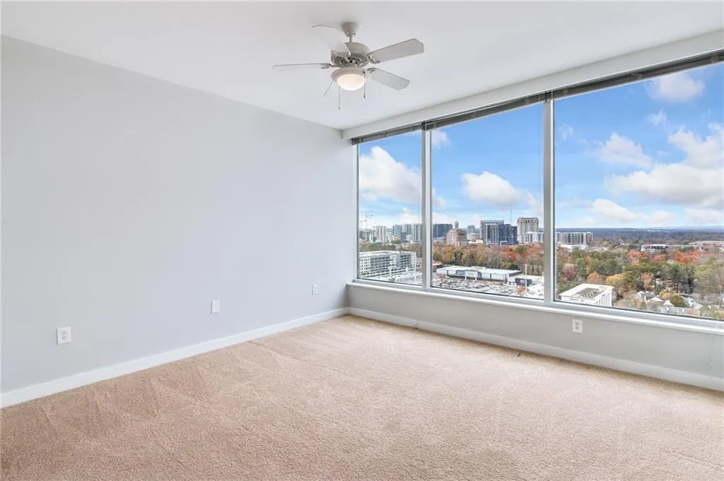 Spare room with carpet flooring, a view of city, and a ceiling fan