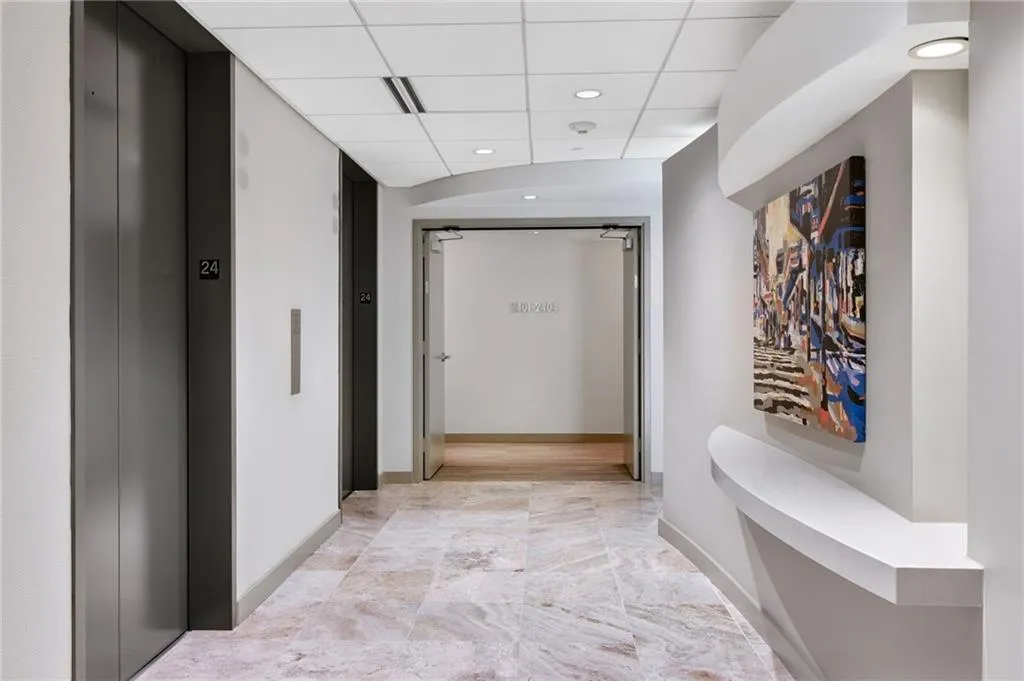 Hallway with elevator, a paneled ceiling, and recessed lighting
