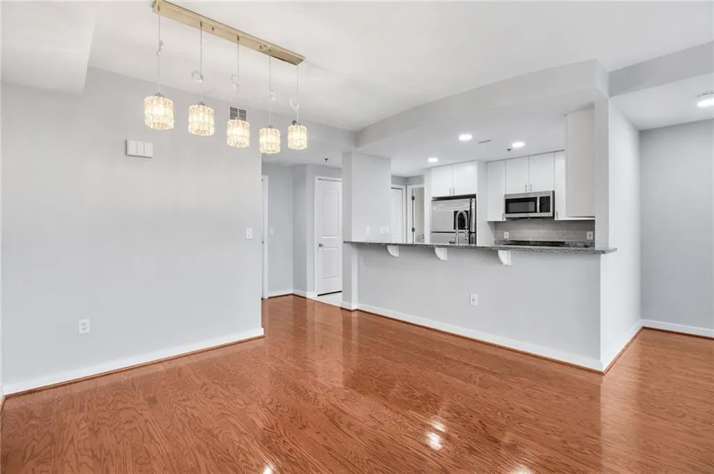 Kitchen with wood finished floors, white cabinets, a breakfast bar area, hanging light fixtures, and recessed lighting