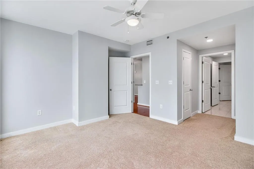 Unfurnished bedroom with light carpet and ceiling fan