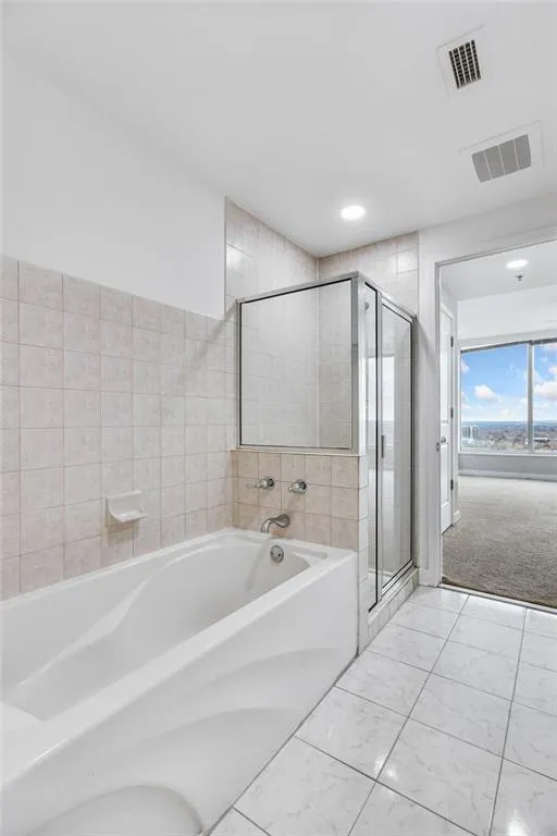 Bathroom featuring a garden tub, a stall shower, marble look tiles, and recessed lighting