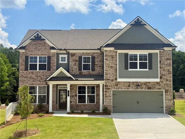 Multi-level facade featuring varied brick and stone accents, a covered front entry, and a two-car garage