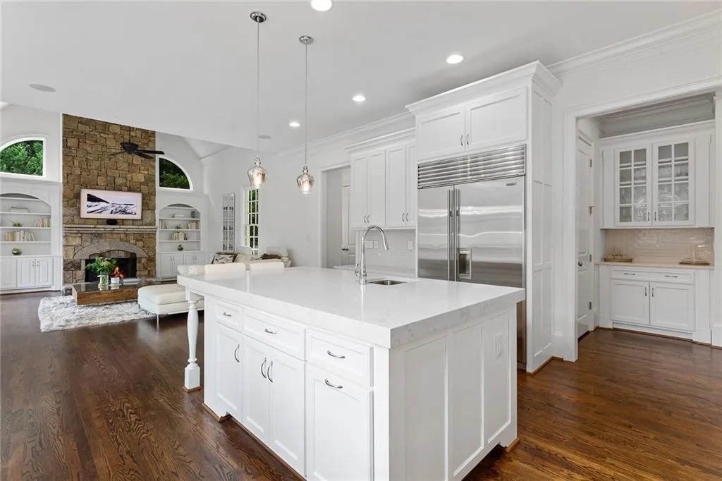 Kitchen with a fireplace, ceiling fan, dark hardwood / wood-style flooring, and white cabinetry