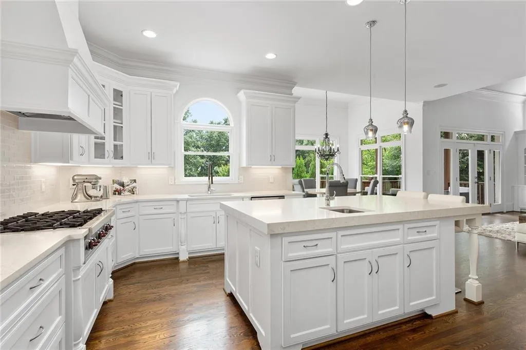 Kitchen with pendant lighting, dark hardwood / wood-style floors, sink, tasteful backsplash, and custom range hood