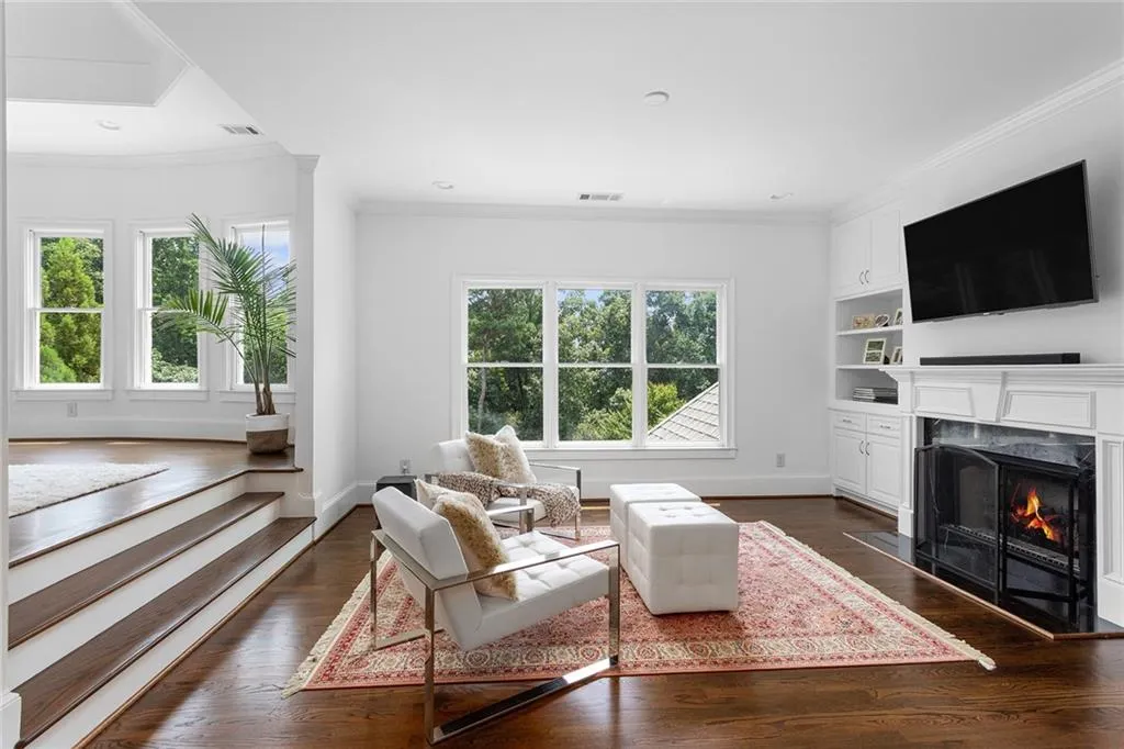Living room with a wealth of natural light, ornamental molding, a fireplace, and dark hardwood / wood-style floors