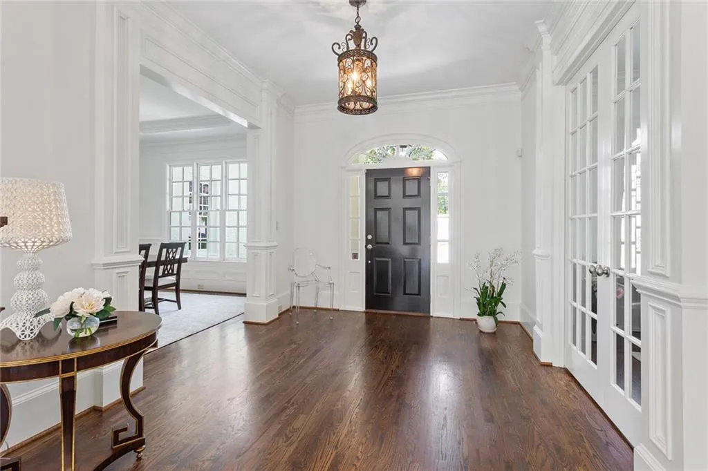 Entrance foyer with crown molding, french doors, a chandelier, a healthy amount of sunlight, and dark hardwood / wood-style flooring