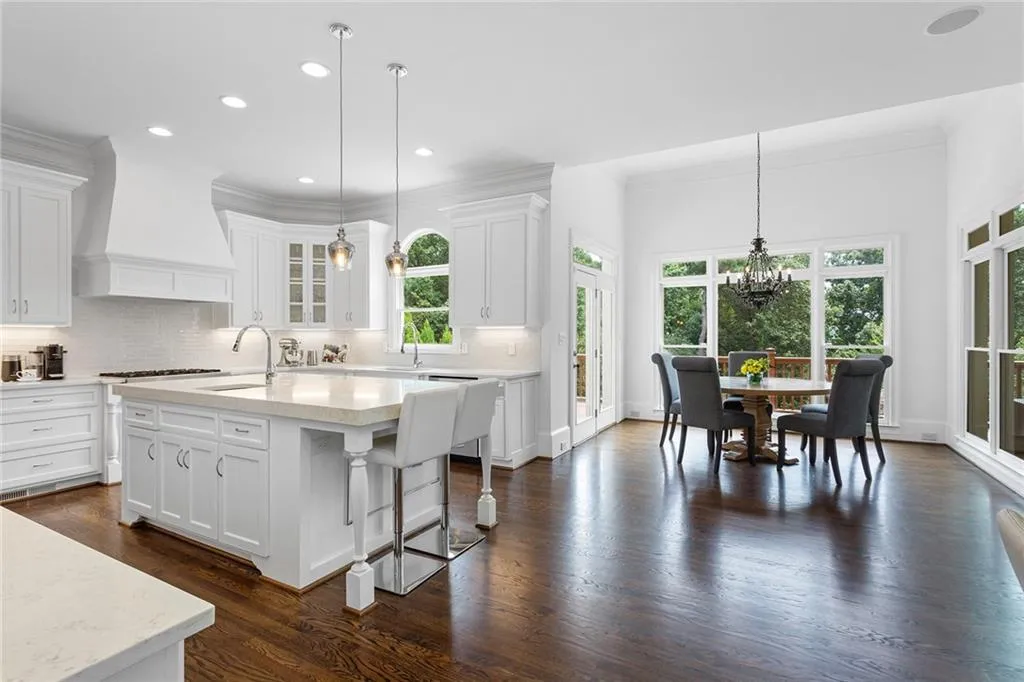 Kitchen featuring a kitchen island with sink, decorative light fixtures, premium range hood, and tasteful backsplash