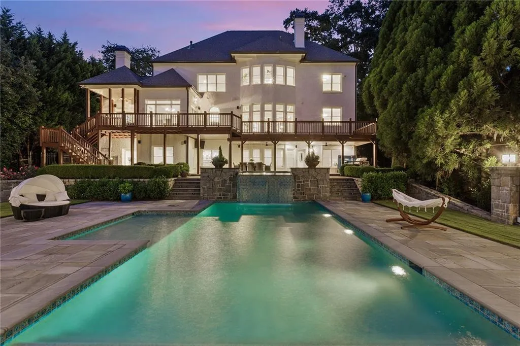 Back house at dusk featuring a balcony and a patio