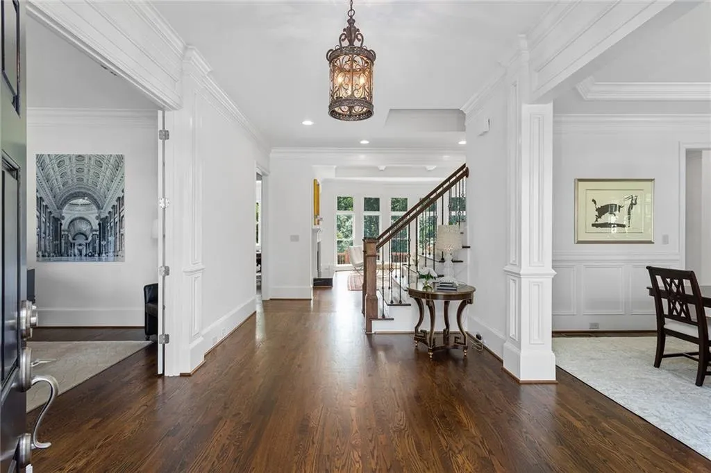 Entrance foyer with crown molding, an inviting chandelier, decorative columns, and dark hardwood / wood-style floors
