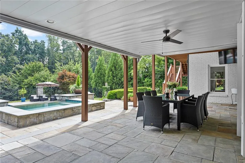 View of patio with ceiling fan and a pool with hot tub