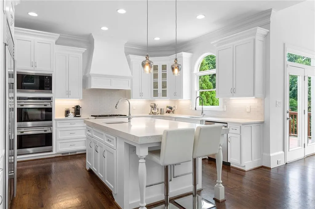 Kitchen featuring dark hardwood / wood-style flooring, tasteful backsplash, stainless steel appliances, and premium range hood