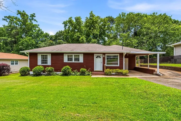 Ranch-style residence featuring red siding and white window shutters