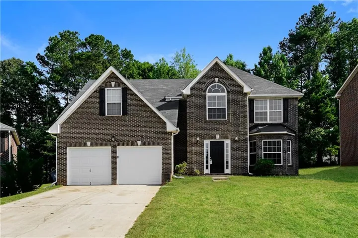 Brick exterior featuring a two-car garage, arched window, and bay window