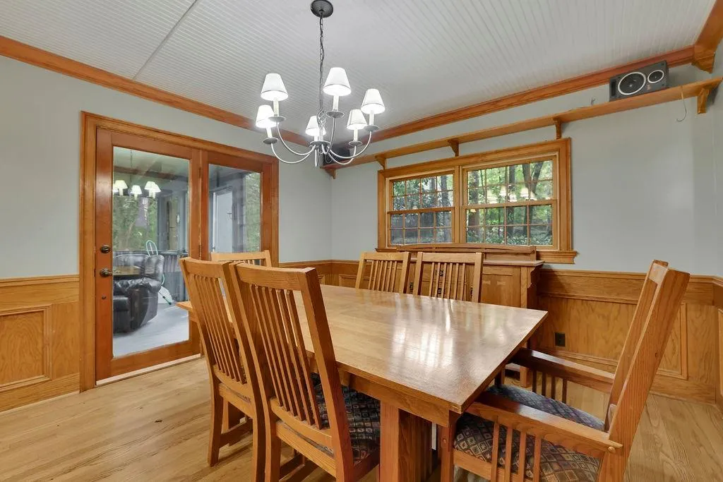 Dining area featuring ornamental molding, light wood-type flooring, wood walls, and a chandelier