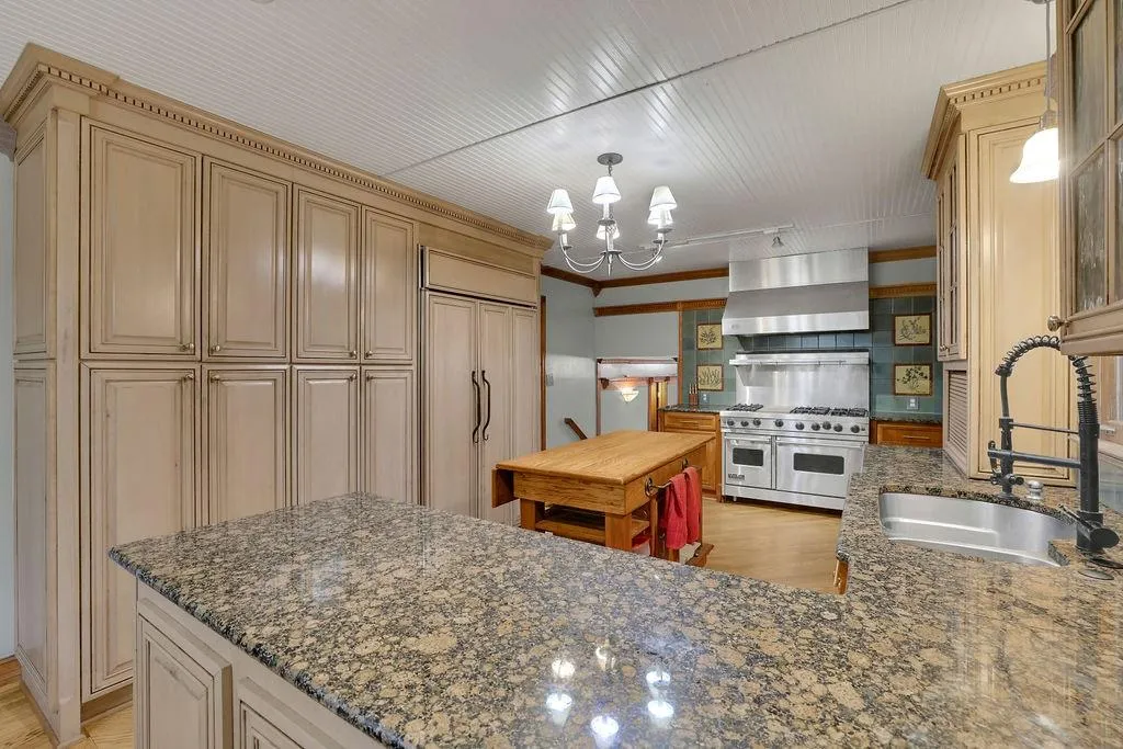 Kitchen featuring light hardwood / wood-style floors, high quality appliances, sink, and wall chimney range hood