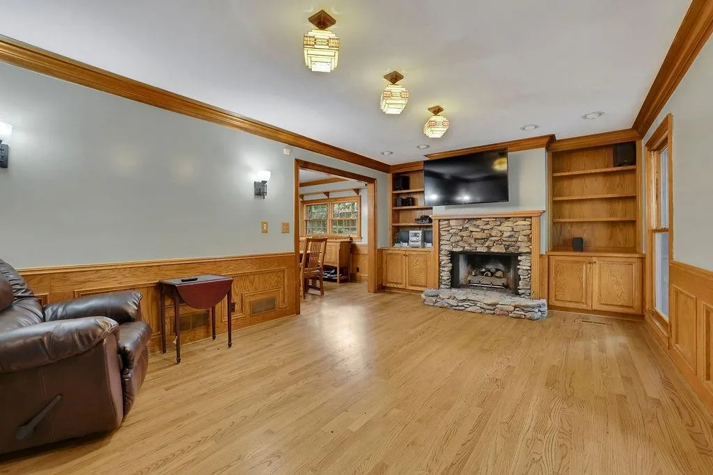 Living room with light wood-type flooring, crown molding, a fireplace, and built in shelves