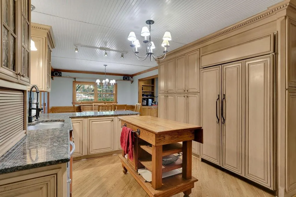 Kitchen featuring hanging light fixtures, light hardwood / wood-style floors, dark stone countertops, sink, and a chandelier