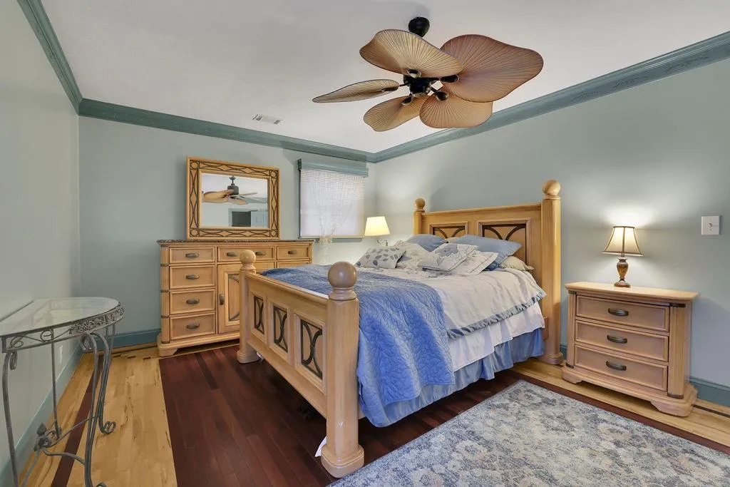 Bedroom with ceiling fan, crown molding, and dark hardwood / wood-style flooring