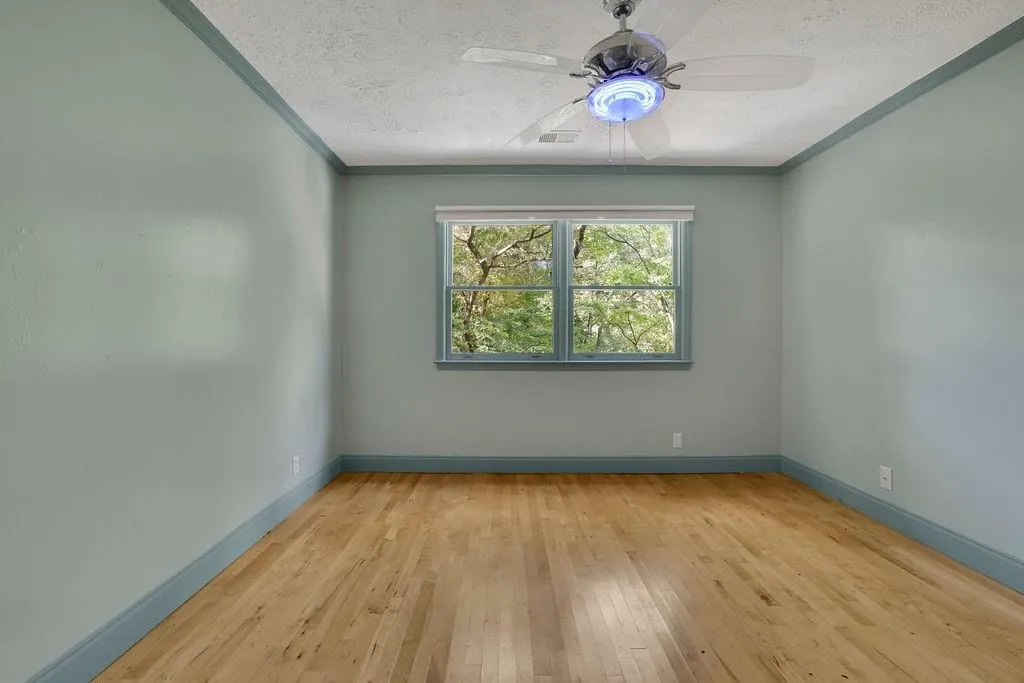 Spare room featuring light wood-type flooring, ceiling fan, a textured ceiling, and crown molding