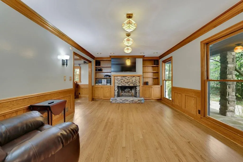 Living room with light hardwood / wood-style floors, crown molding, a fireplace, and built in features