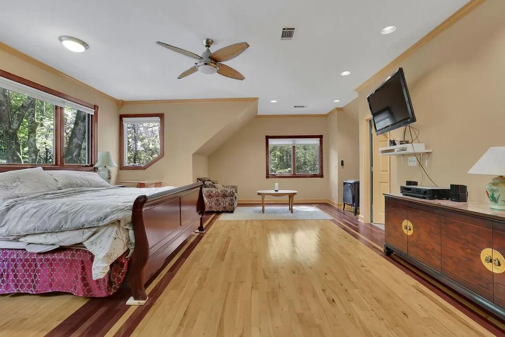 Bedroom featuring light hardwood / wood-style floors, multiple windows, and ceiling fan