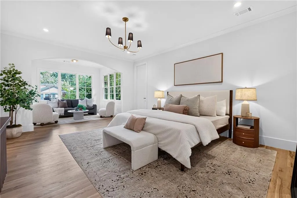 Spacious room featuring wood-finish flooring, a contemporary chandelier, recessed lighting, and large windows with transom elements