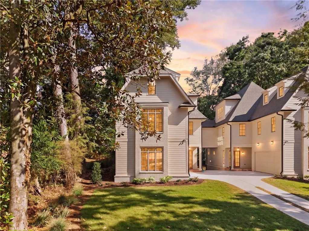 Exterior featuring light-colored siding, multiple dormer windows, a two-car garage, established trees, and a concrete driveway