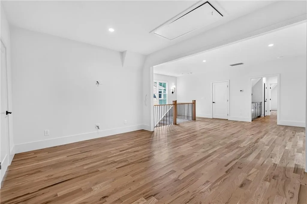 Expansive open room featuring wood-finish flooring, recessed lighting, and a staircase with a wood and metal railing