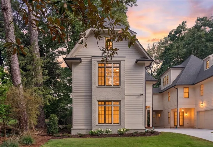 Two-story residence featuring light-toned siding and brick, dark-framed windows, a multi-gabled roofline, and a paved driveway
