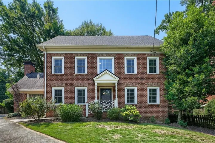 Traditional brick exterior with white trim, featuring a central entry porch with white columns and railing