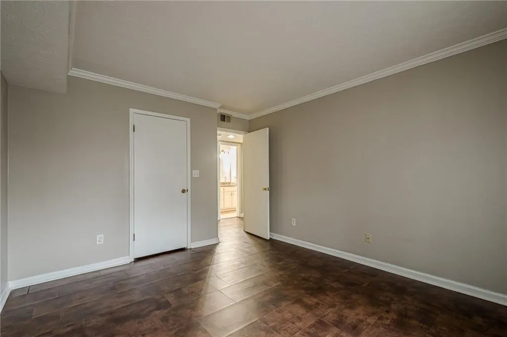 Empty room featuring crown molding and dark wood-type flooring