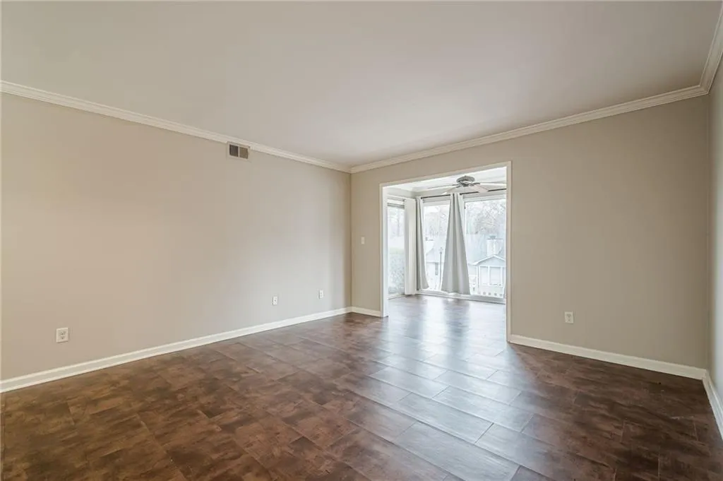 Empty room featuring ornamental molding and dark wood-type flooring