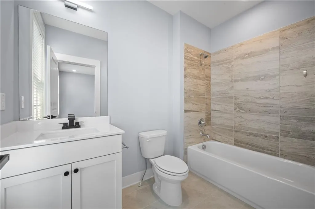 Bathroom with shower / bathtub combination, vanity, tile patterned flooring, toilet, and baseboards