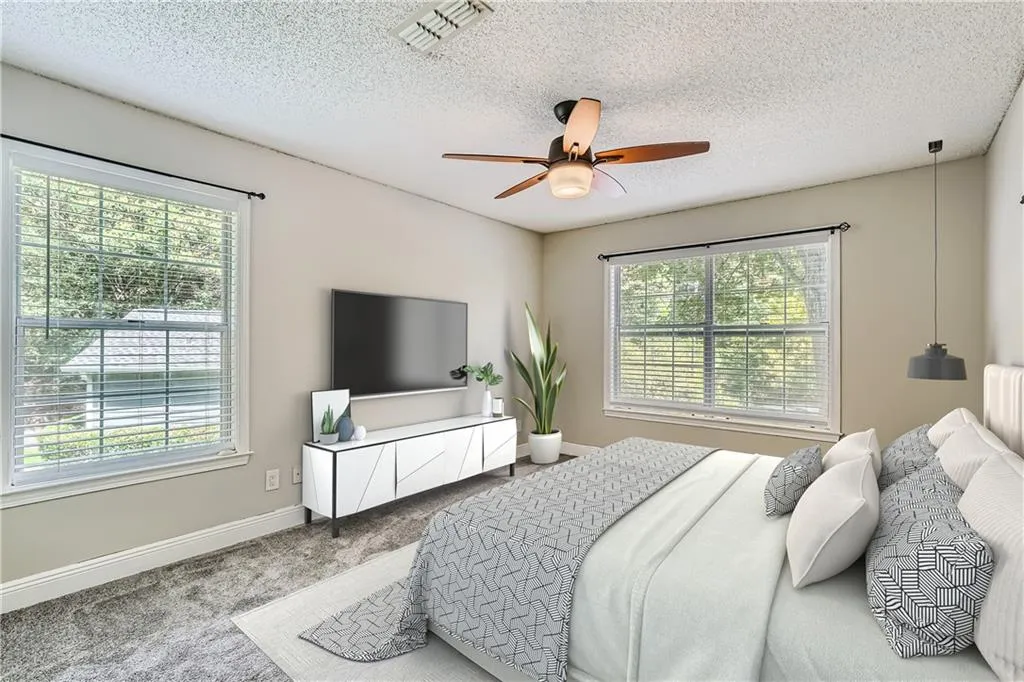 Carpeted bedroom with a textured ceiling, ceiling fan, and multiple windows