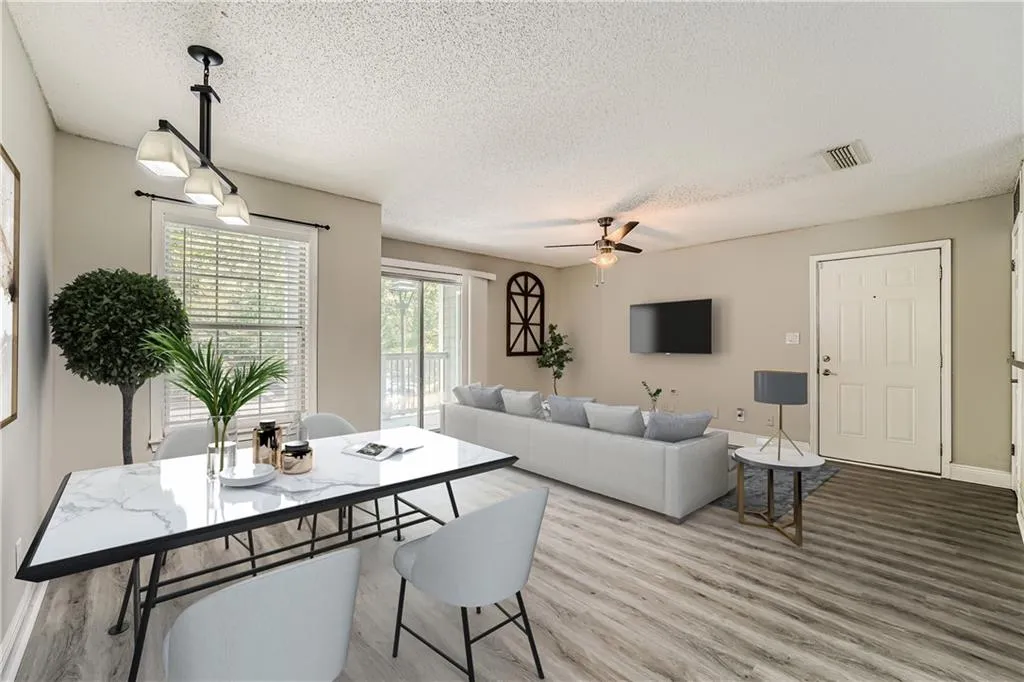 Living room featuring a textured ceiling, ceiling fan, and light wood-type flooring