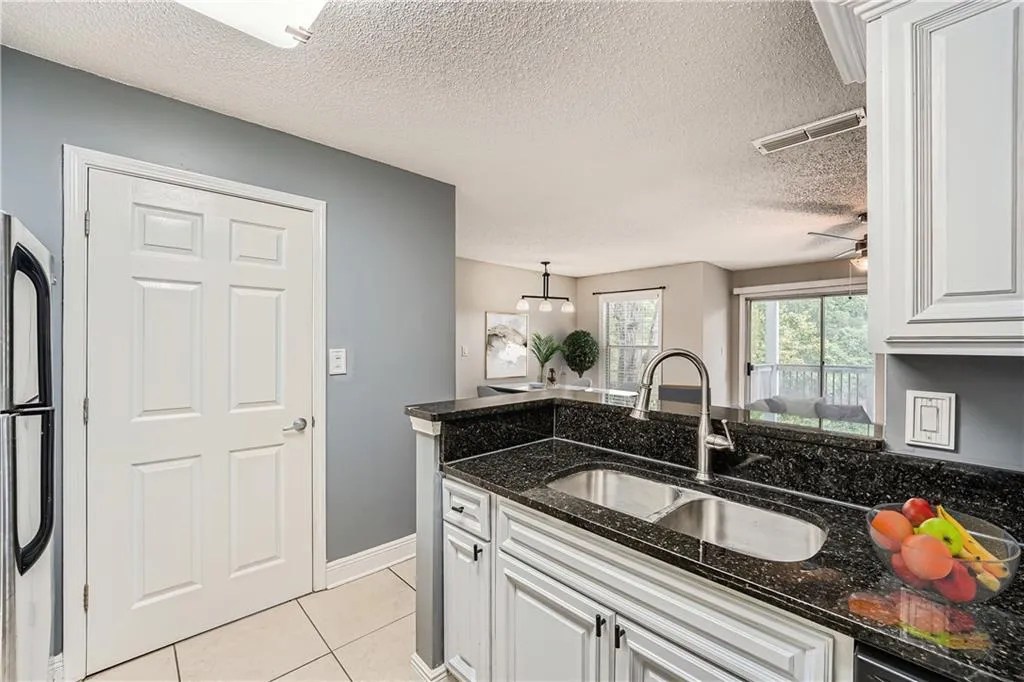 Kitchen with dark stone counters, white cabinetry, and sink