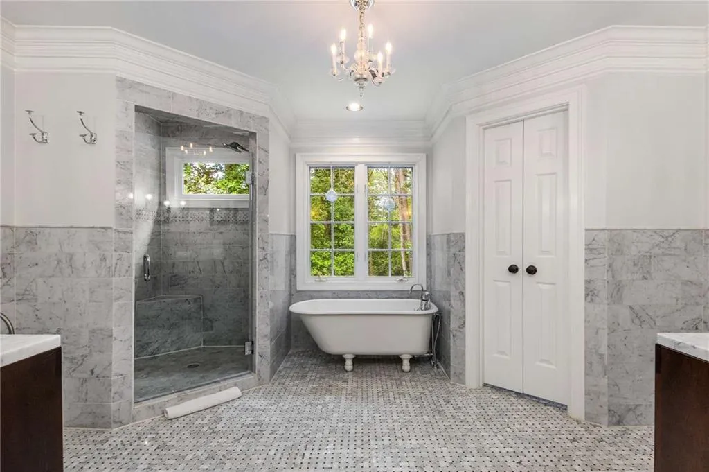 The primary bath features marble tiled wainscot and marble mosaic floor