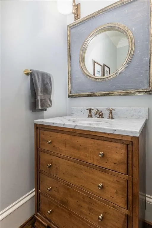 The main level powder room features a marble topped furniture vanity and bespoke mirror