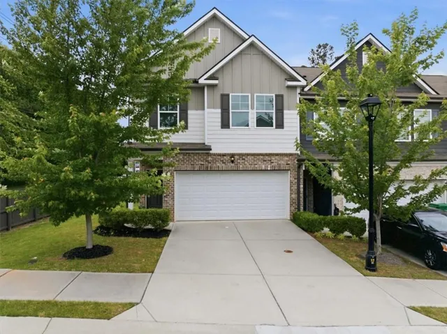Contemporary two-story exterior featuring a two-car garage, brick accents, and a covered entry