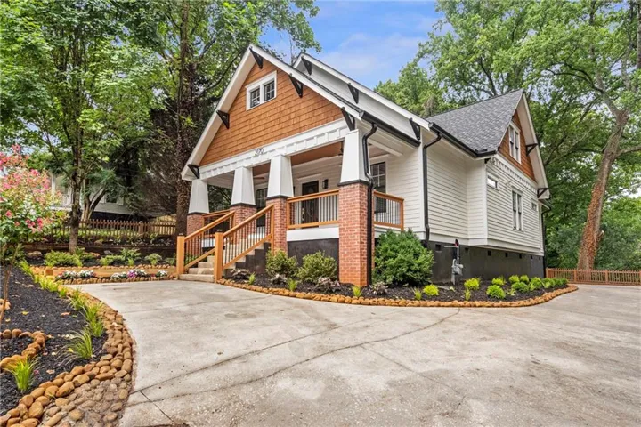 Craftsman-style home featuring a covered front porch with brick pillars, a gabled roofline with shake siding accents, and a concrete driveway