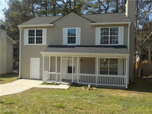 Traditional-style house featuring covered porch, a front lawn, a chimney, and a shingled roof