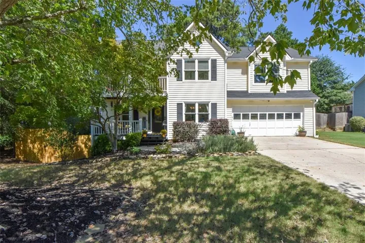 Two-story exterior with siding, a two-car garage, front porch, and mature trees
