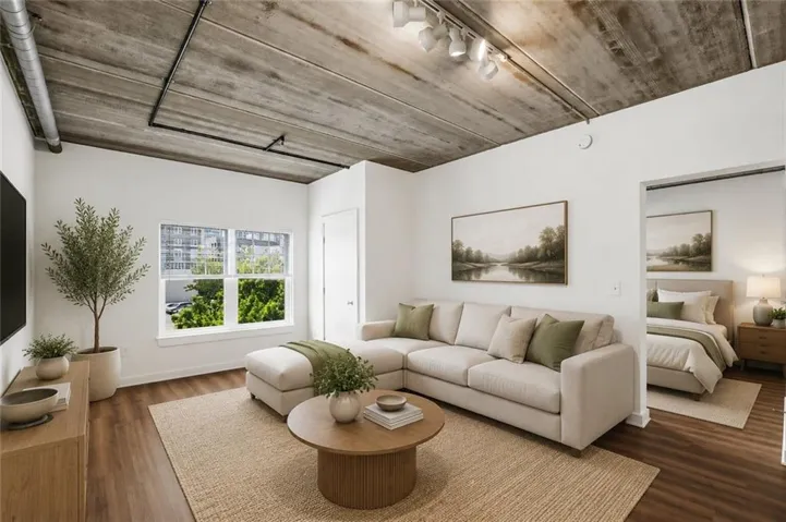 Living area featuring a concrete ceiling with exposed ductwork, track lighting, and wood-finish flooring
