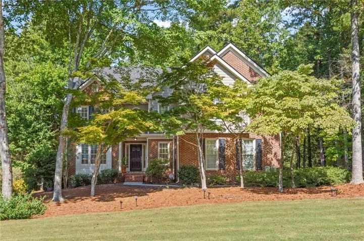 Brick and siding exterior featuring gabled rooflines, dark shutters, and a covered entry