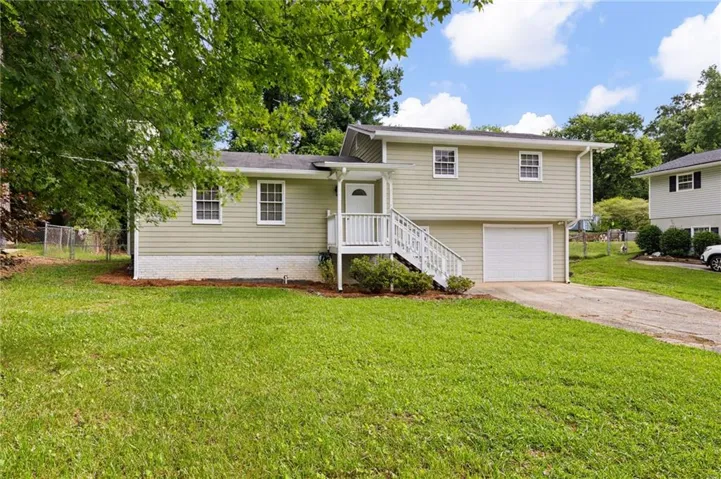 Split-level residence featuring a light-colored siding exterior, white trim windows, and a prominent front entrance with white railings